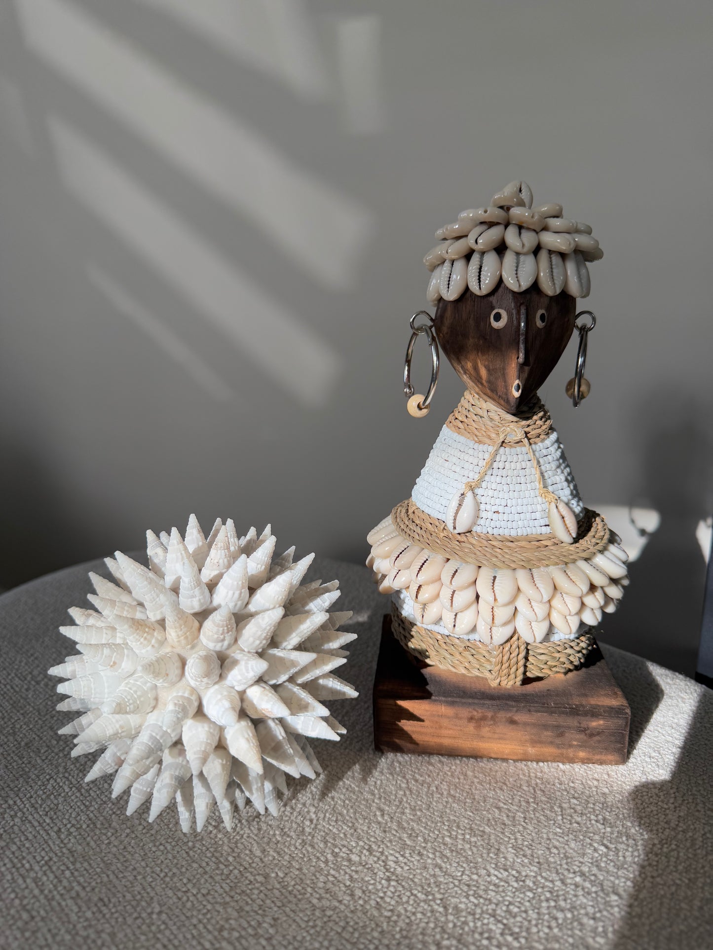 Handgemaakte Namji Doll houten pop van circa 25 cm met witte glaskralen, kauri schelpen en oorbellen, uniek cultureel decoratiestuk