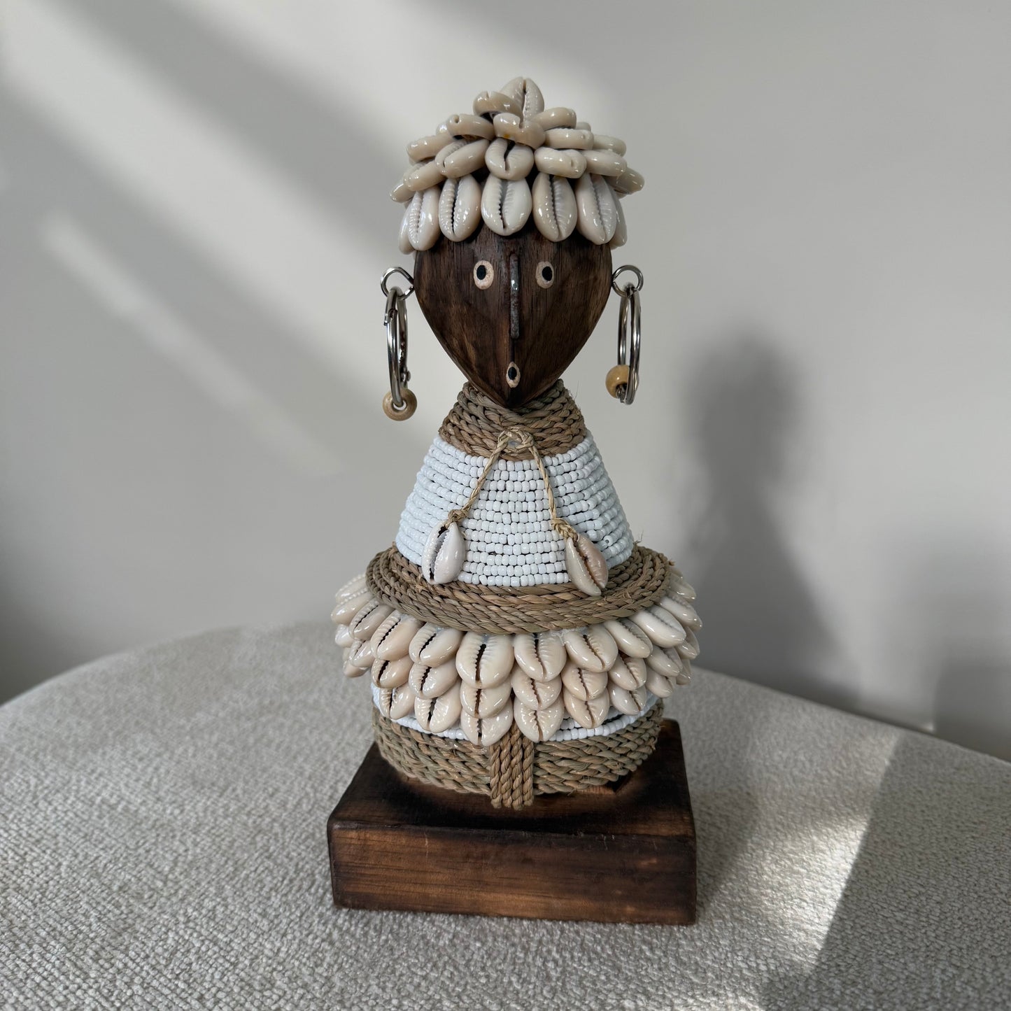 Handgemaakte Namji Doll houten pop van circa 25 cm met witte glaskralen, kauri schelpen en oorbellen, uniek cultureel decoratiestuk
